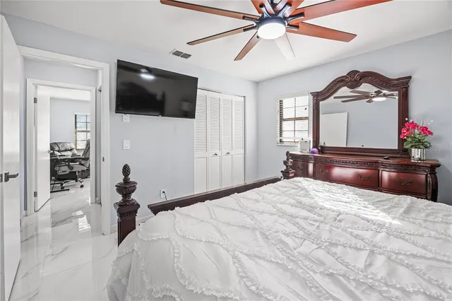 a bedroom with a bed and a flat tv screen on dresser