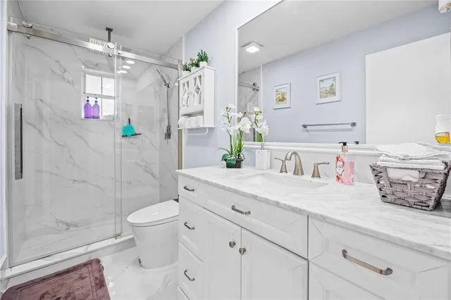 a bathroom with a granite countertop sink a toilet and shower