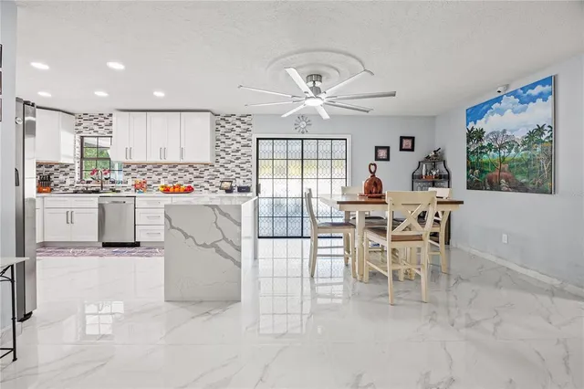 a dining room filled chandelier and kitchen view