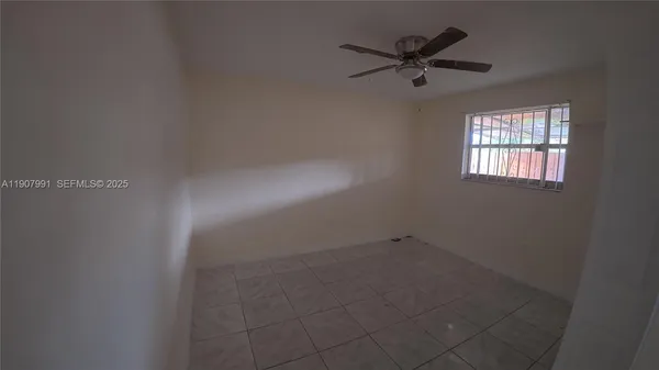 an empty room with a ceiling fan and window