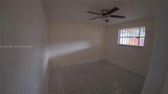 an empty room with a ceiling fan and window