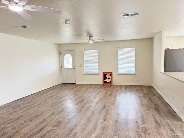 an empty room with windows and fan