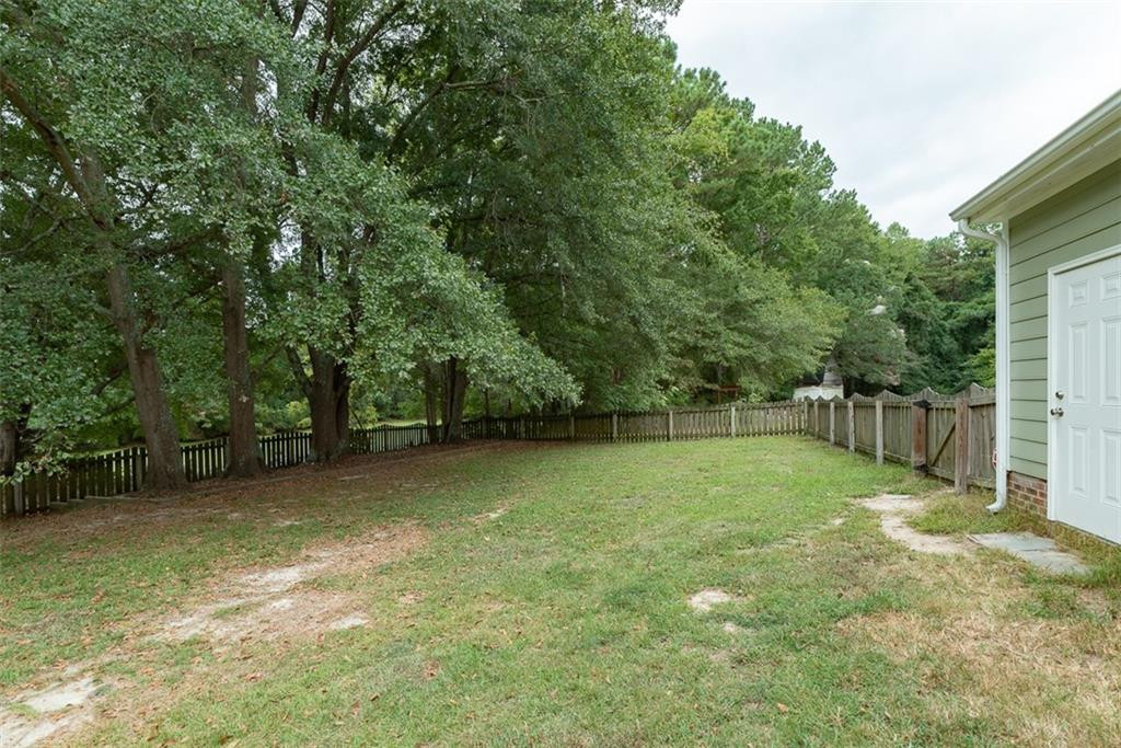 9317 Meadow Rue Place Raleigh, NC 27603 - Photo 29 of 36 a backyard of a house with lots of plants and large tree