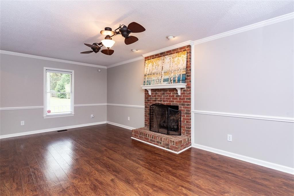9317 Meadow Rue Place Raleigh, NC 27603 - Photo 7 of 36 an empty room with wooden floor fireplace and windows