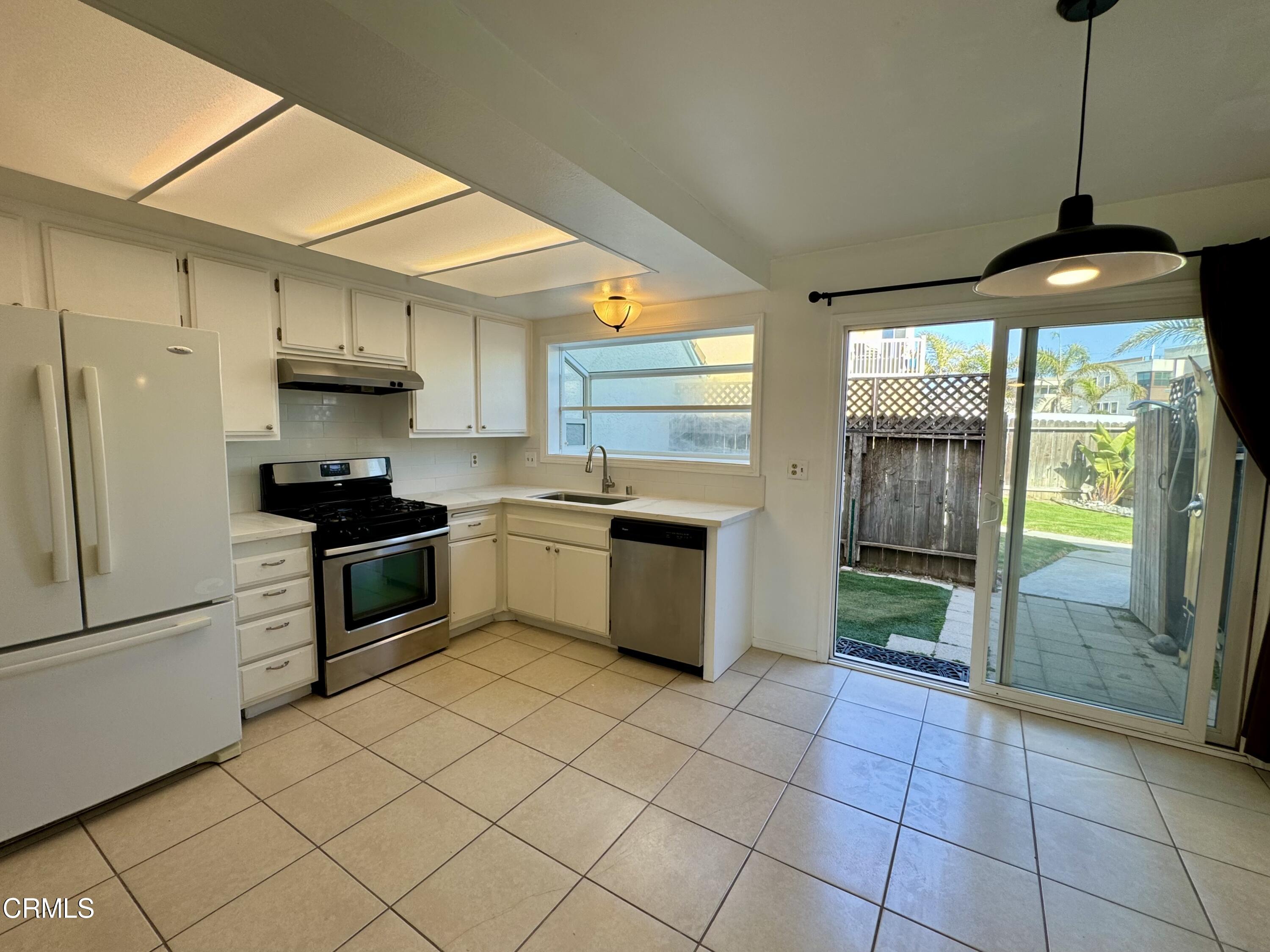 1031 Dunes Street, Unit D Oxnard, CA 93035 - Photo 6 of 26 a kitchen with a stove a sink dishwasher a refrigerator and a microwave oven