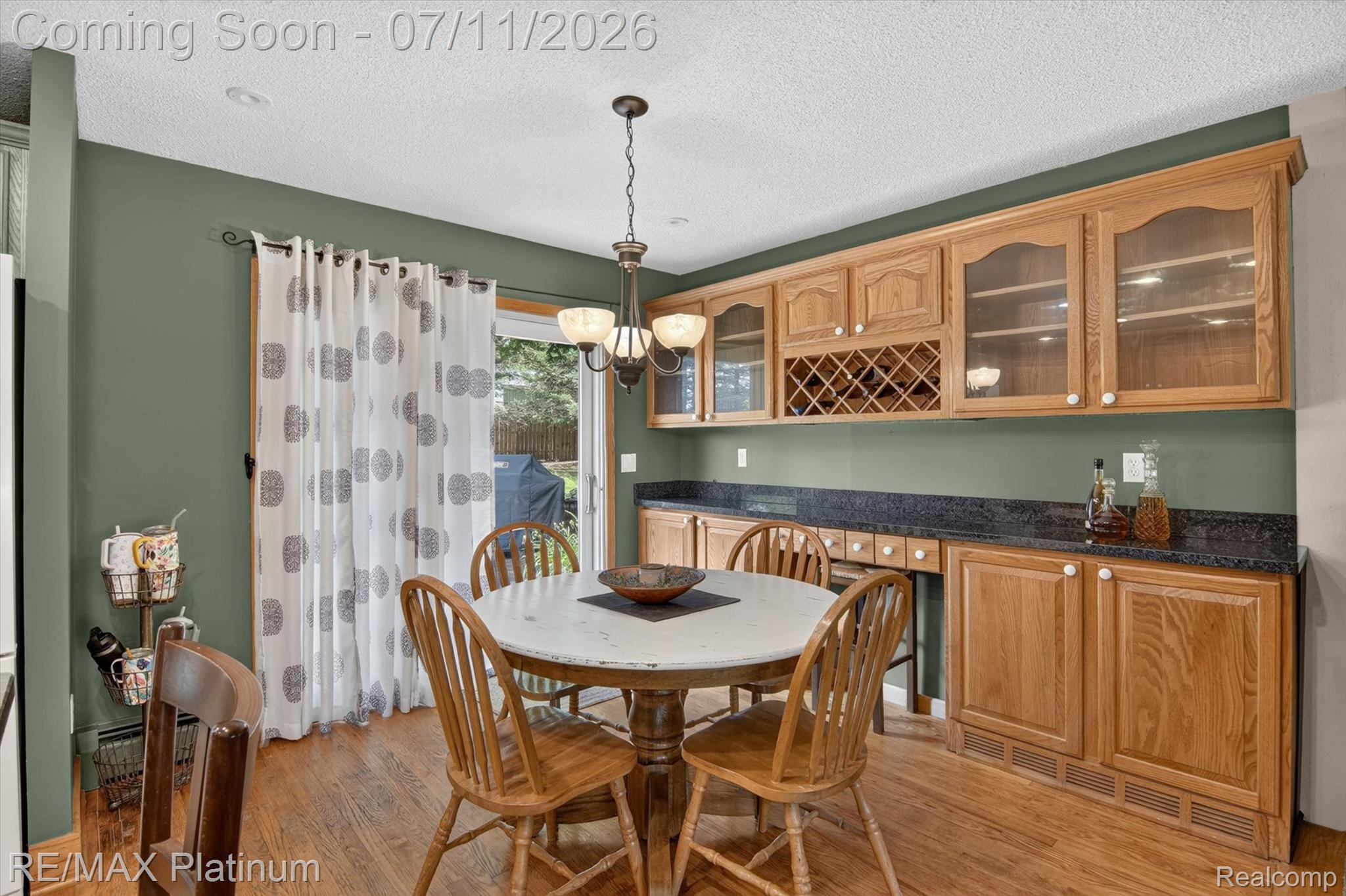 13365 North Territorial Road Gregory, MI 48137 - Photo 16 of 52 Dining area featuring wood-finish flooring, a built-in buffet with glass-front cabinetry, a wine rack, and a sliding glass door