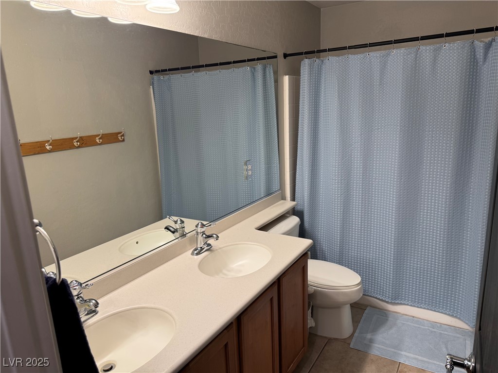 5522 Porcupine Rim Street Las Vegas, NV 89130 - Photo 17 of 28 Full bathroom featuring light tile patterned flooring, double vanity, and a shower with curtain
