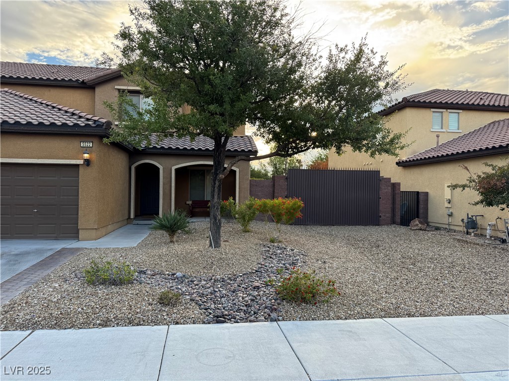 5522 Porcupine Rim Street Las Vegas, NV 89130 - Photo 2 of 28 View of front facade featuring a gate, stucco siding, an attached garage, and a tiled roof