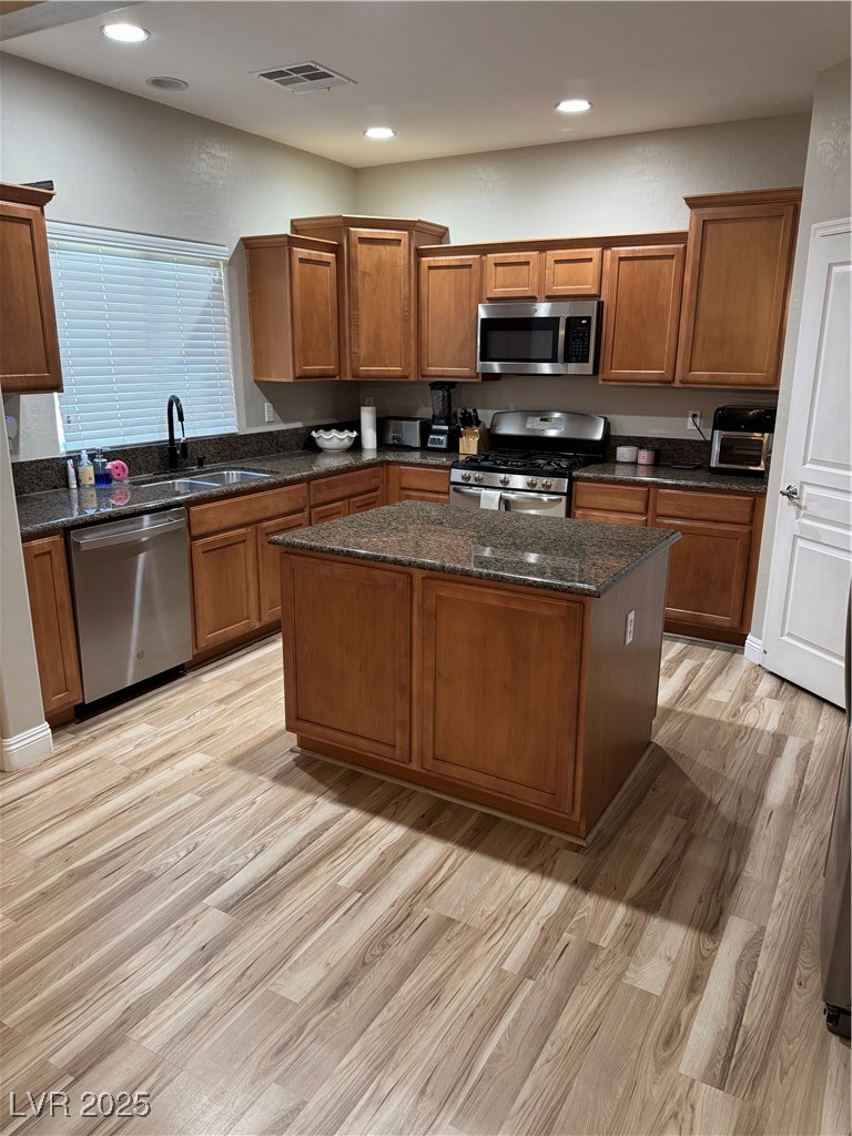 5522 Porcupine Rim Street Las Vegas, NV 89130 - Photo 4 of 28 Kitchen featuring range, light wood-style floors, dark stone counters, brown cabinetry, and dishwasher
