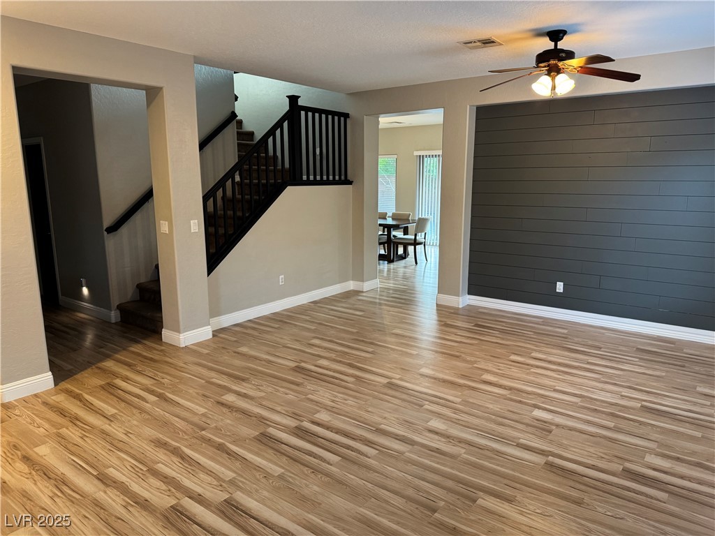 5522 Porcupine Rim Street Las Vegas, NV 89130 - Photo 5 of 28 Unfurnished room featuring light wood finished floors, stairway, and ceiling fan