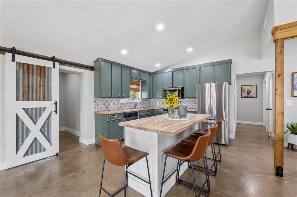 286 Benevolence Way China Spring, TX 76633 - Photo 11 of 37 Open-concept kitchen featuring sage green cabinetry, a patterned tile backsplash, stainless steel appliances, and a central island with a wood-finish countertop