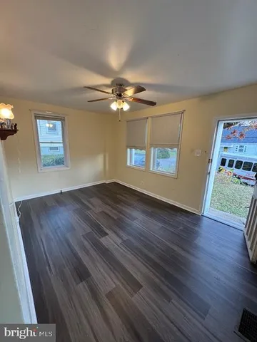 a view of an empty room with window and wooden floor