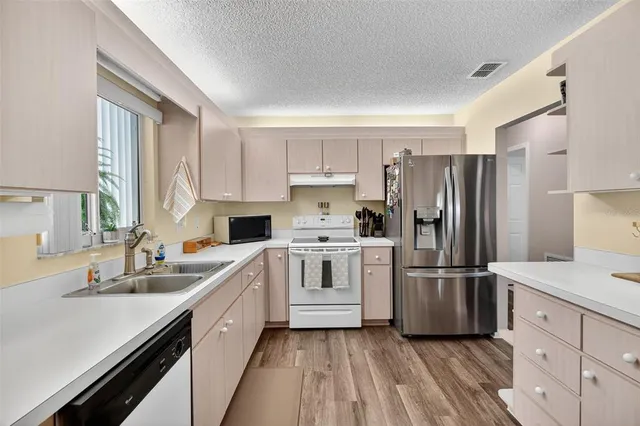 a kitchen with cabinets stainless steel appliances a sink and wooden floor