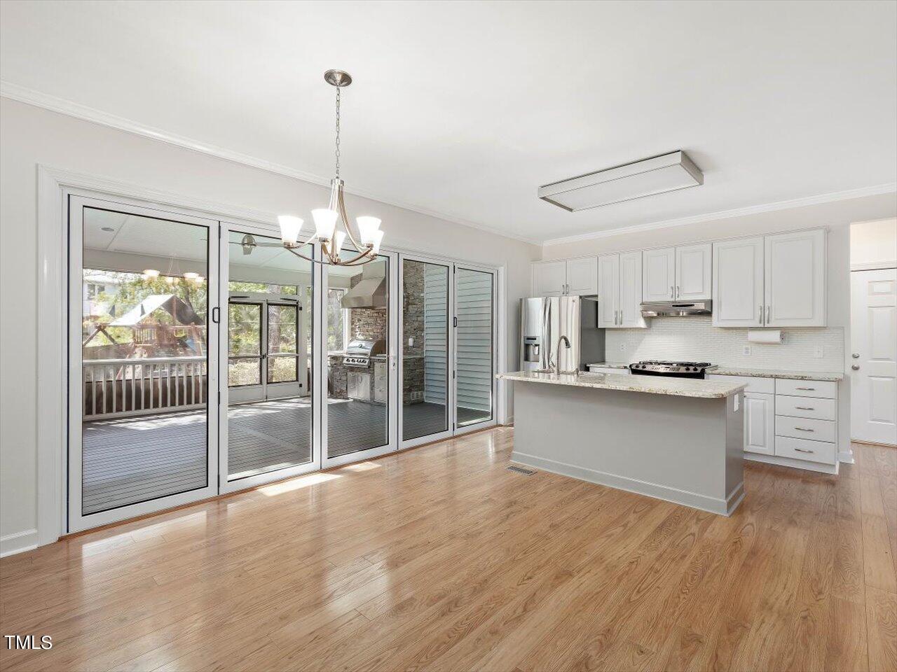 7001 Three Bridges Circle Raleigh, NC 27613 - Photo 3 of 25 a kitchen with stainless steel appliances granite countertop a refrigerator a sink dishwasher a oven and a dining table with wooden floor