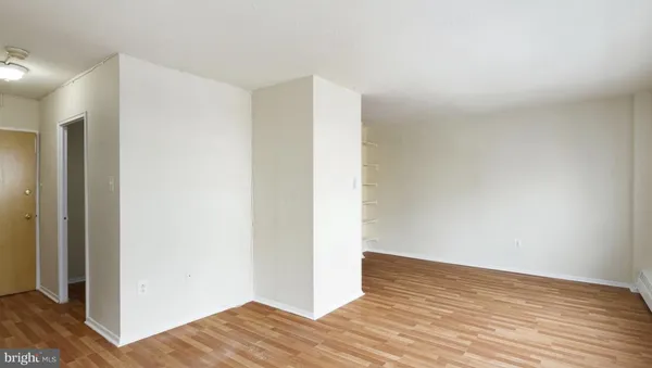 a view of an empty room with wooden floor and closet