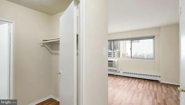 a view of an empty room with wooden floor and a window
