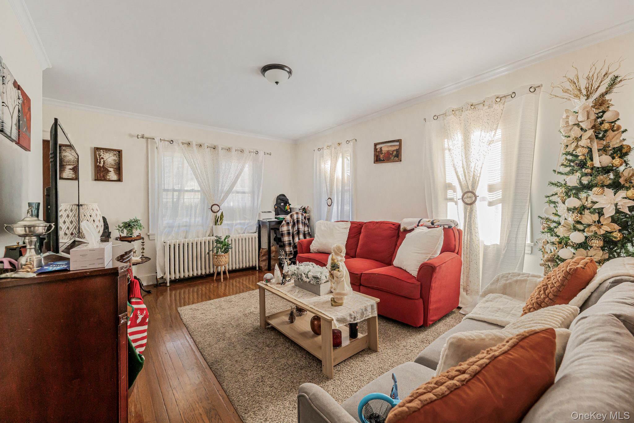 168 Stephenson Boulevard New Rochelle, NY 10801 - Photo 15 of 21 Living area with radiator heating unit, plenty of natural light, crown molding, and hardwood / wood-style flooring