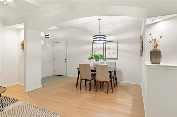 a dining room with wooden floor a chandelier a wooden table and chairs