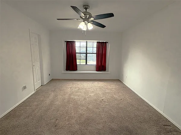 an empty room with windows and ceiling fan
