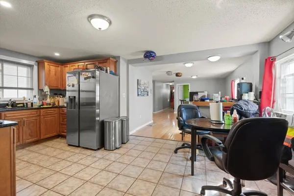a kitchen with stainless steel appliances kitchen island granite countertop a refrigerator a stove a sink dishwasher and a dining table with wooden floor