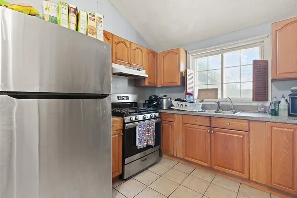 a kitchen with stainless steel appliances granite countertop a refrigerator a sink a stove and white cabinets