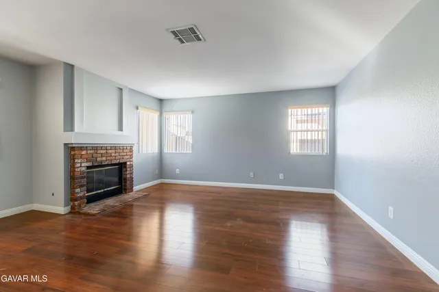 a view of empty room with a fireplace and wooden floor