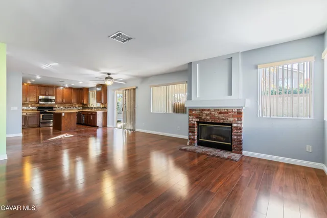 a living room with stainless steel appliances kitchen island hard wood floors and fireplace