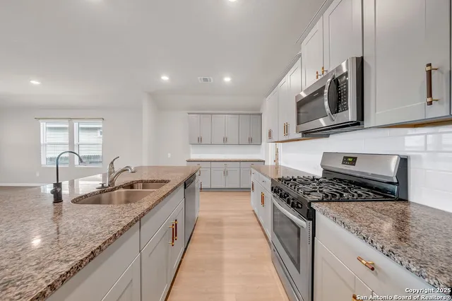 a large kitchen with stainless steel appliances granite countertop a lot of counter space and wooden floors