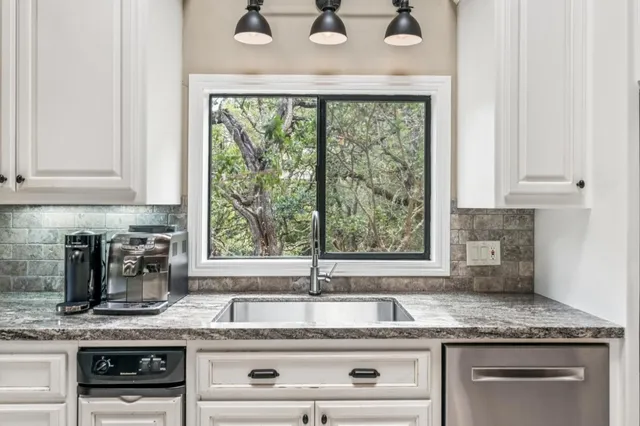 a kitchen with granite countertop a sink window and cabinets