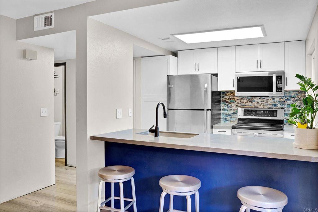 11923 Royal Road, Unit D El Cajon, CA 92021 - Photo 1 of 1 a kitchen with stainless steel appliances a dining table and chairs