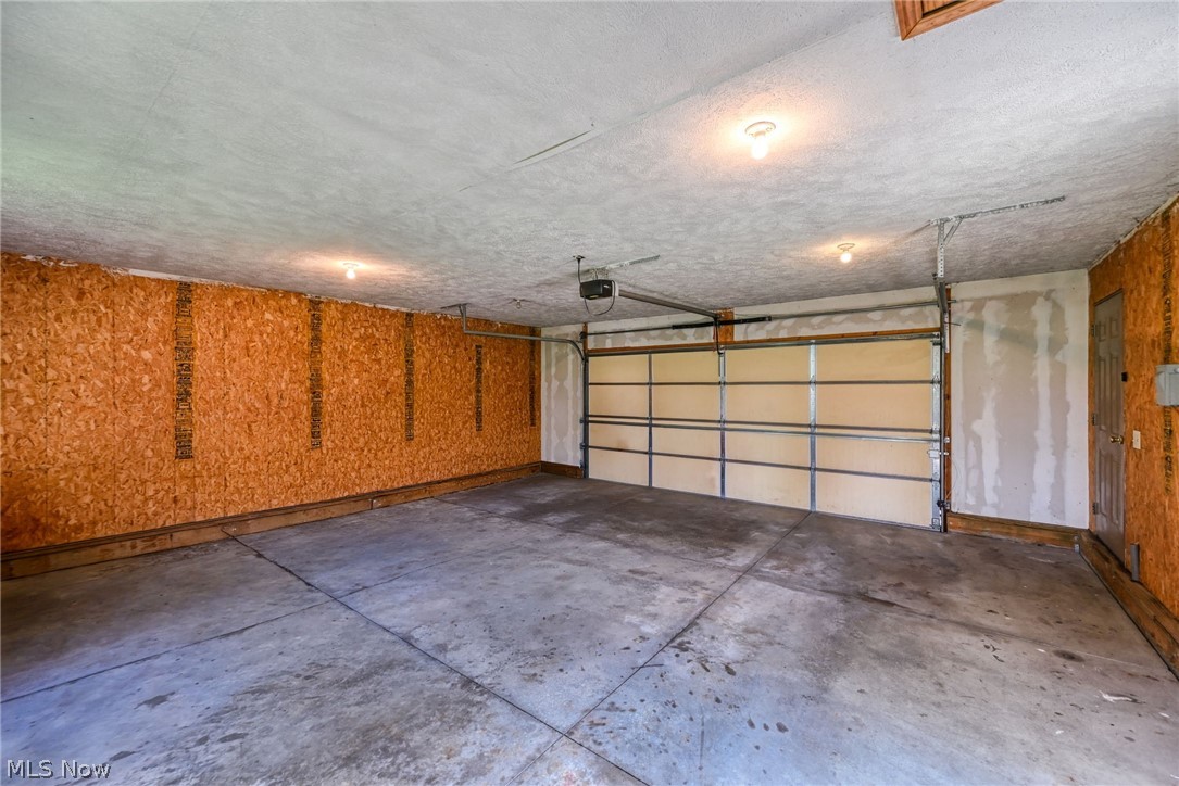 6503 Garrett Road Ravenna, OH 44266 - Photo 20 of 50 Attached garage with a concrete floor, exposed wood-finish wall panels, and overhead lighting
