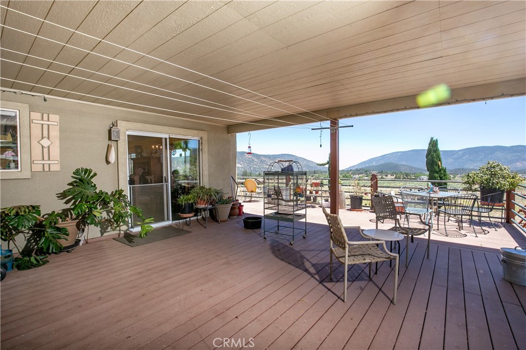 10960 Steinhoff Road Frazier Park, CA 93225 - Photo 46 of 46 An impressive outdoor living space perfect for entertaining. This large, covered wooden deck features a spacious layout with room for multiple seating arrangements, a dining area, and potted plants, all framed by a sturdy railing overlooking stunning, panoramic mountain and valley views.
