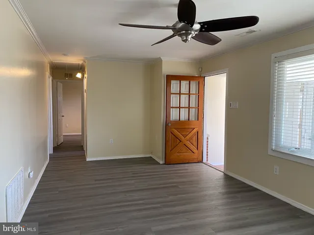an empty room with wooden floor chandelier fan and windows