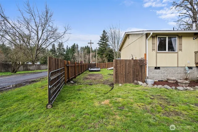 a view of backyard with wooden fence and a large tree