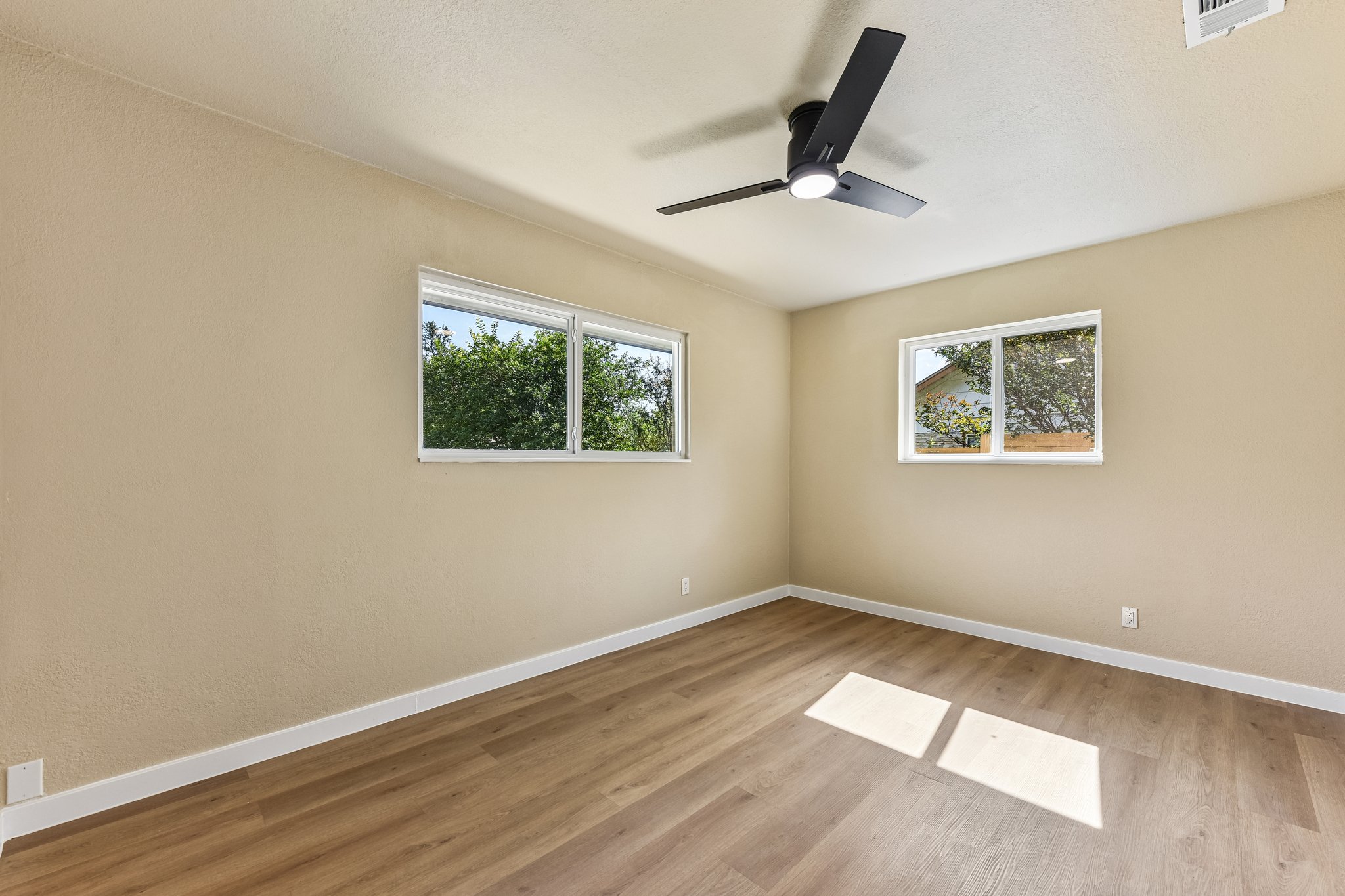 7523 Glenhill Road Austin, TX 78752 - Photo 23 of 38 Natural light bathes this bedroom, offering wood flooring and views of verdant trees.