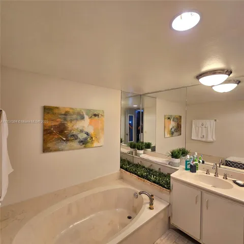 a bathroom with a tub a sink and mirror