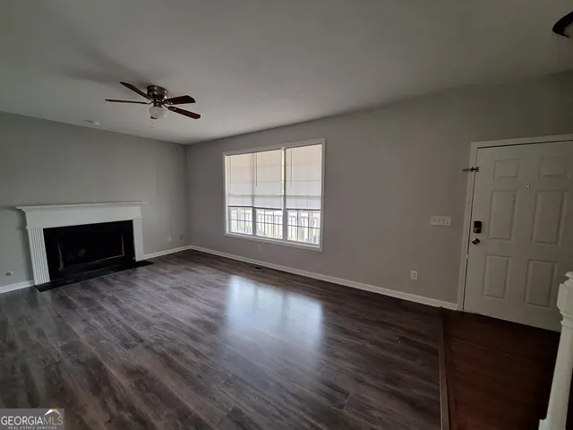 an empty room with wooden floor fireplace and windows