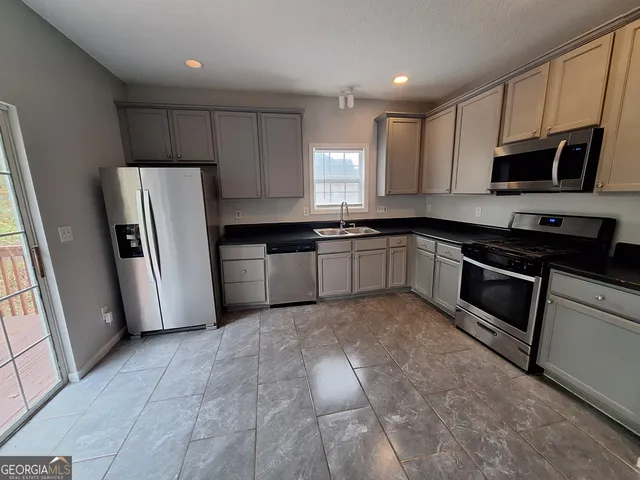 a kitchen with stainless steel appliances granite countertop a refrigerator sink stove microwave and cabinets