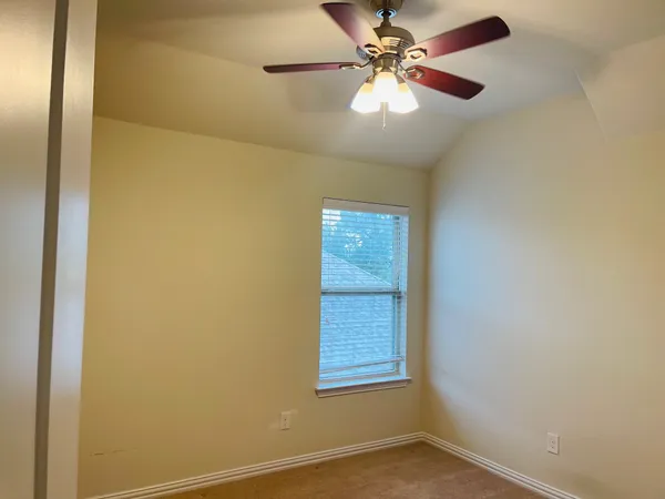 an empty room with a window and a fan