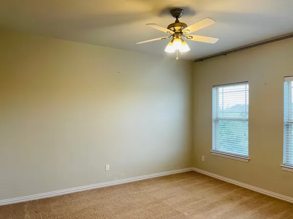 an empty room with windows and chandelier fan
