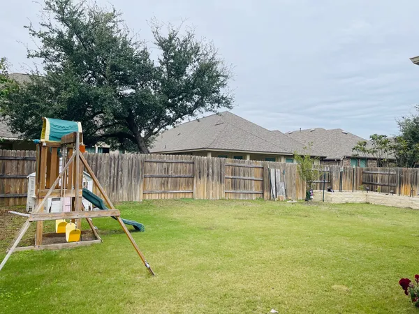 a view of a house with a yard and a large tree