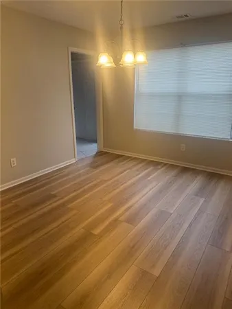 a view of an empty room with window and wooden floor