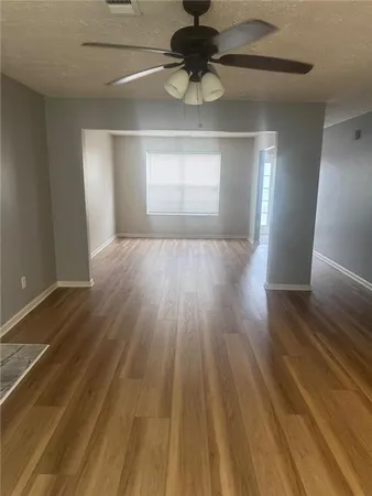 a view of empty room with wooden floor and fan