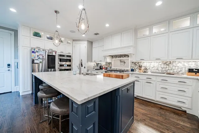 a kitchen with stainless steel appliances kitchen island granite countertop a table chairs sink and cabinets