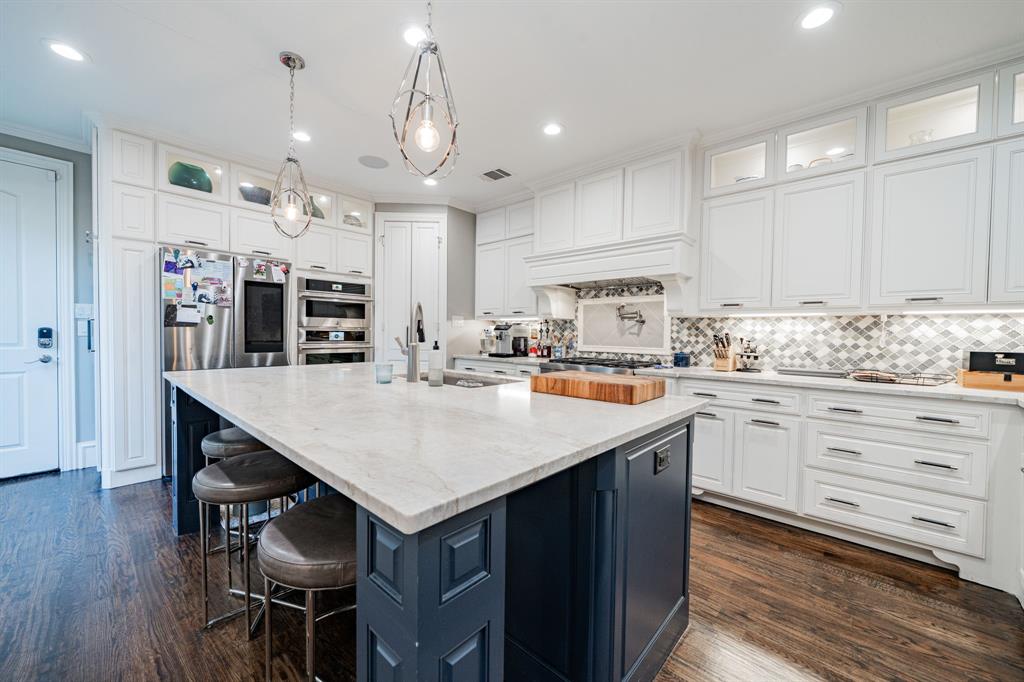 a kitchen with stainless steel appliances kitchen island granite countertop a table chairs sink and cabinets