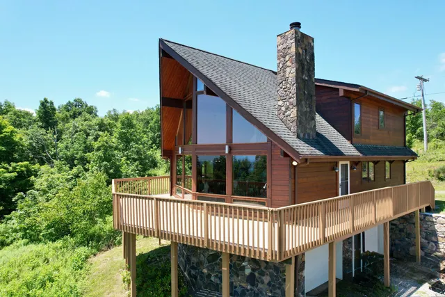 a view of a house with large trees and wooden fence