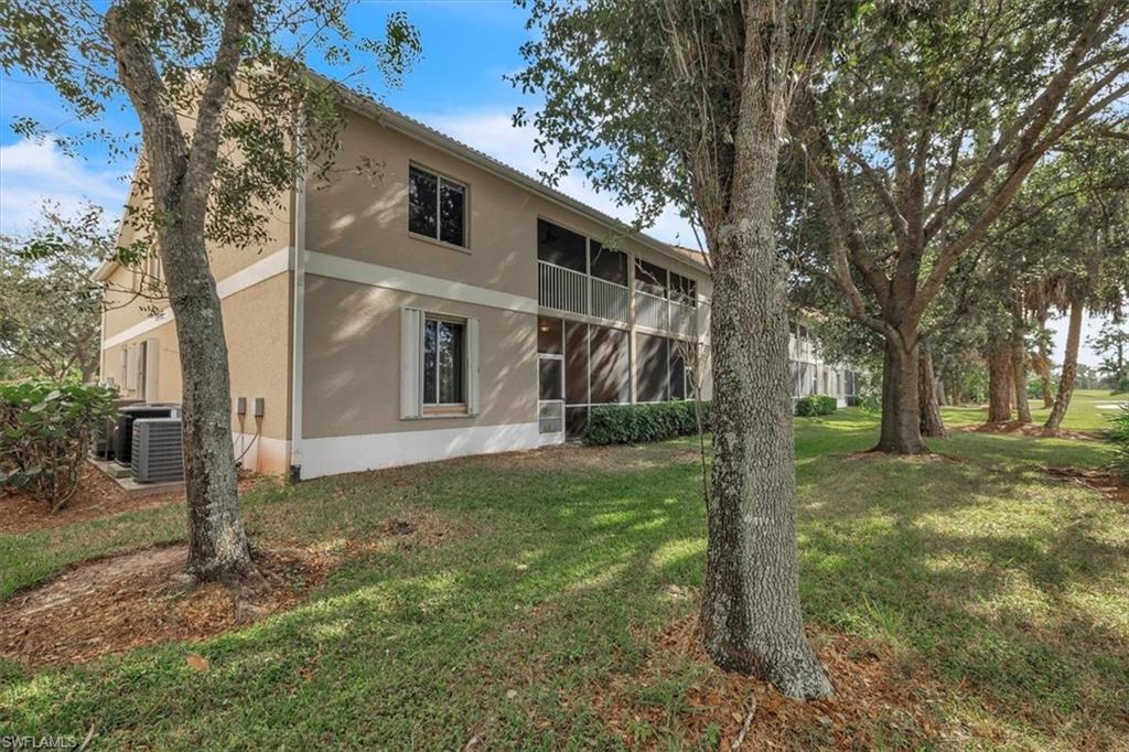 8075 Tiger Cove, Unit 1706 Naples, FL 34113 - Photo 35 of 50 Back of house featuring a sunroom, stucco siding, and a yard
