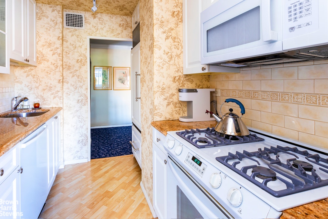 530 East 72nd Street, Unit 9B Manhattan, NY 10021 - Photo 6 of 18 a kitchen with a stove and a wooden cabinets