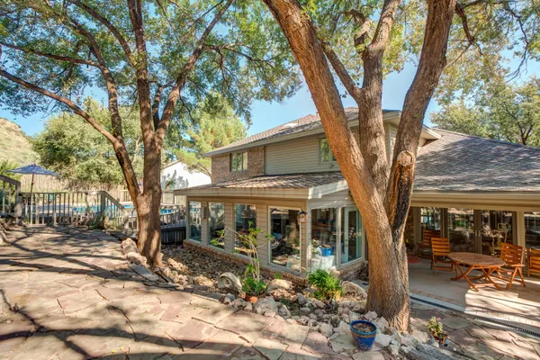 a view of a white house with a large tree and wooden fence