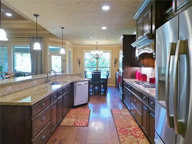 a kitchen with stainless steel appliances granite countertop a refrigerator a stove and a sink